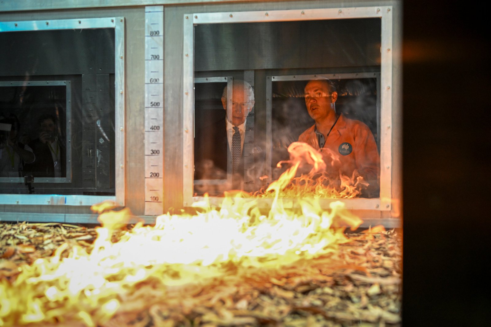 Britain's King Charles III listens to researcher Dr. Matt Plucinski, right, describes "Pyrotron" combustion wind tunnel during a visit to the CSIRO National Bushfire Behavior Research Laboratory in Canberra