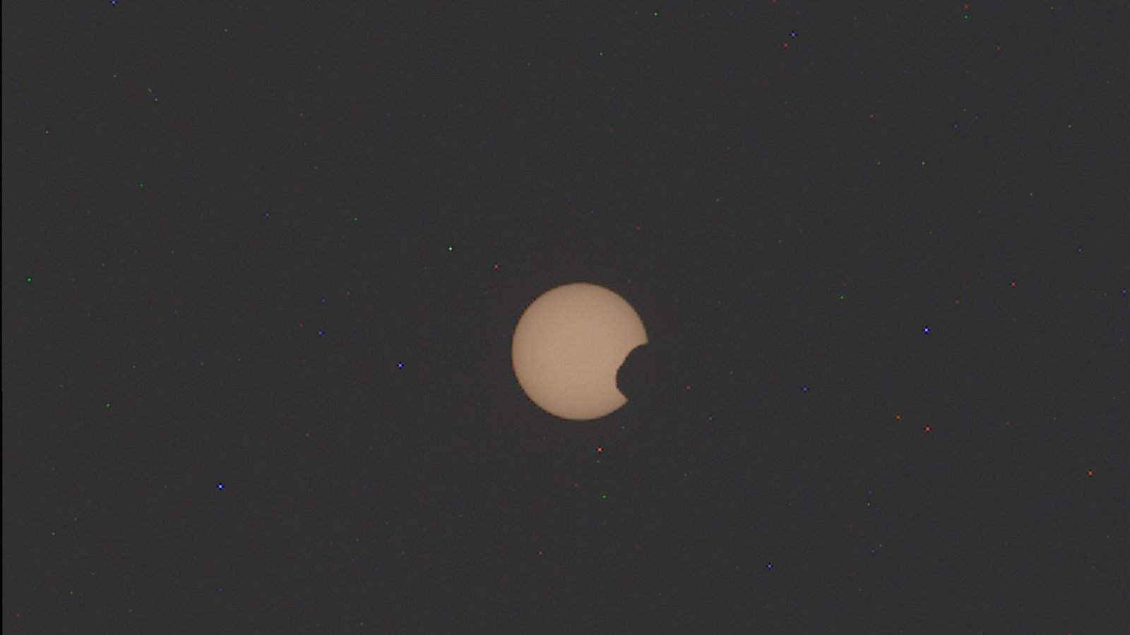 photo of the yellow-orange Sun partially eclipsed by the potato-shaped Martian moonphobo