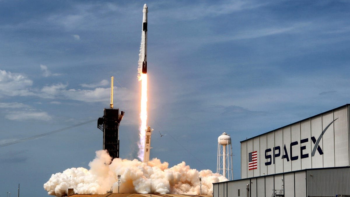 a rocket launches near a SpaceX building