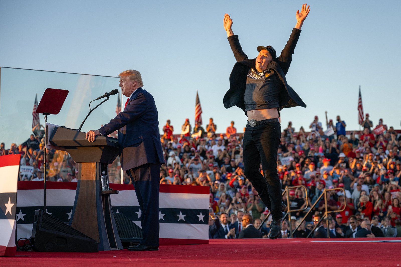 Tesla CEO Elon Musk (R) jumps on stage as he joins Donald Trump during a campaign mounting in Butler, Pennsylvania on October 5, 2024