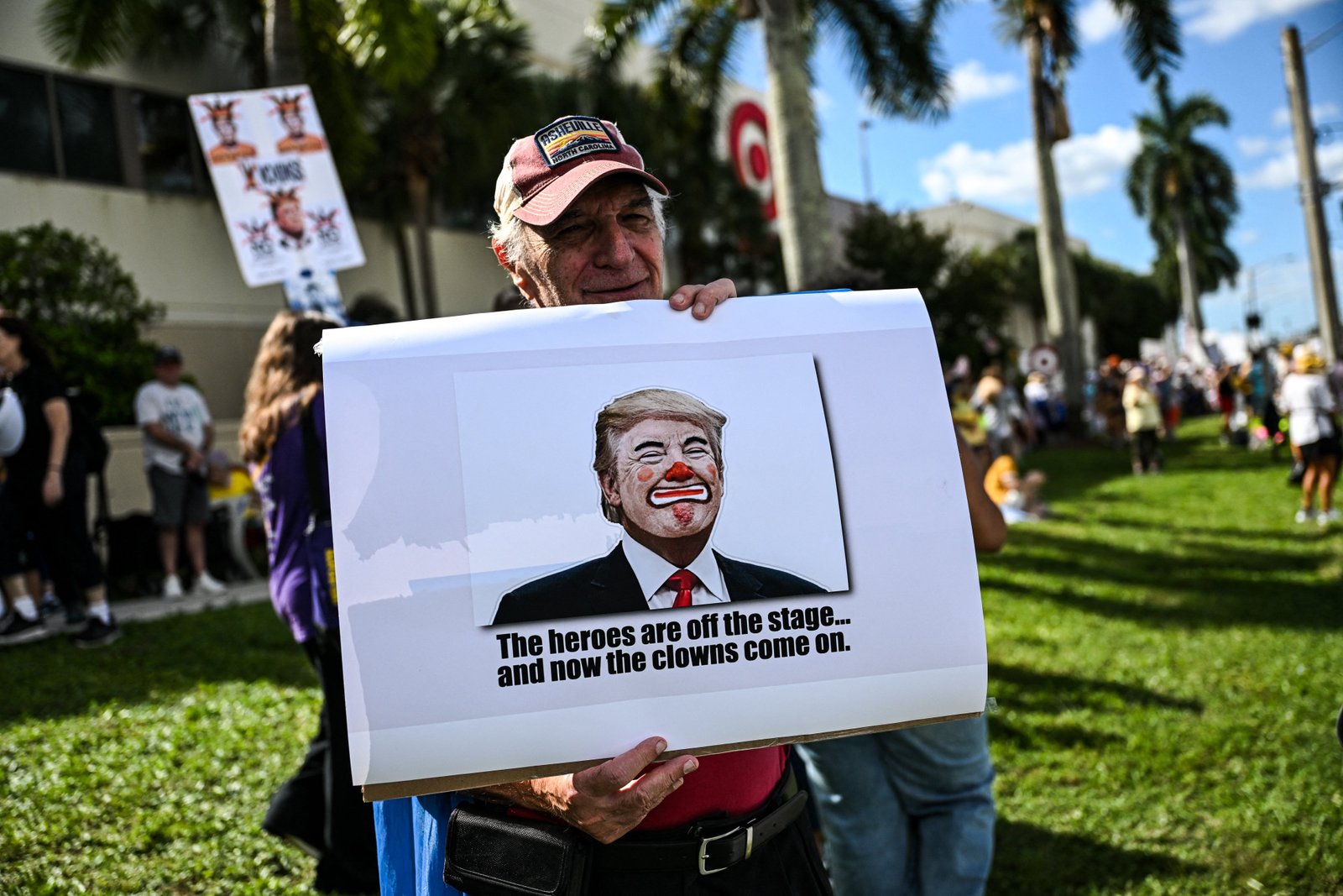 The protester holds up a sign that reads: 'The heroes are off the stage... and now the clowns are coming in'