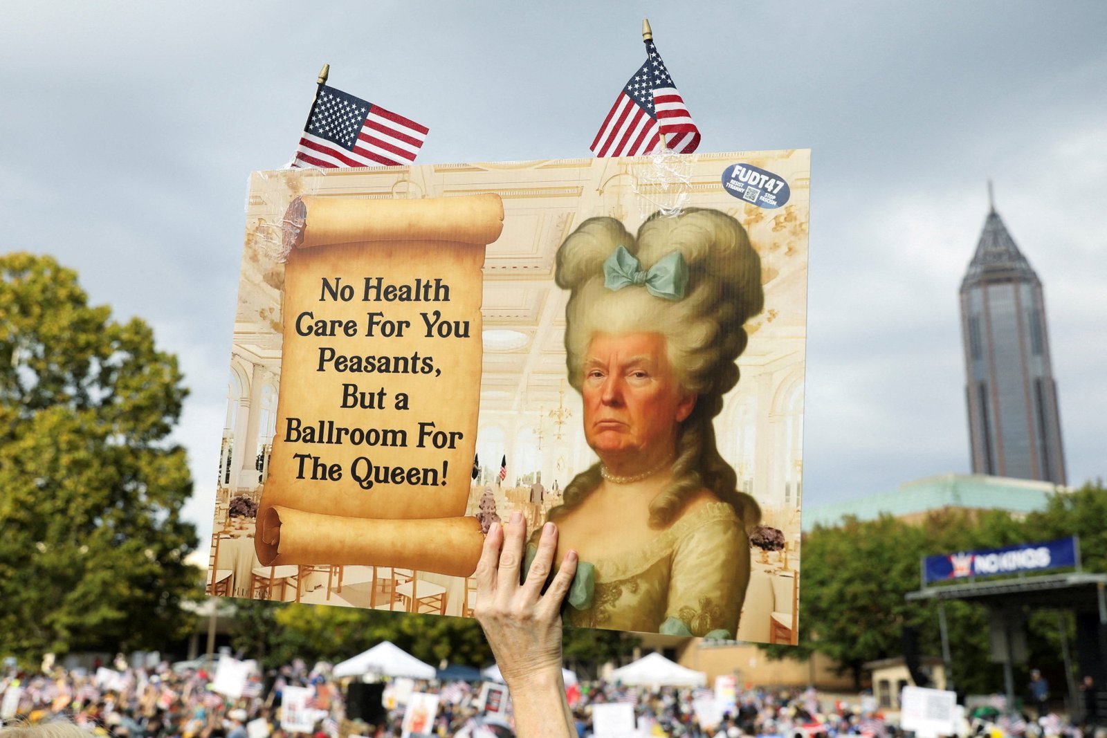 A person holds a placard with an image depicting Trump as Marie Antoinette at the rally in Atlanta
