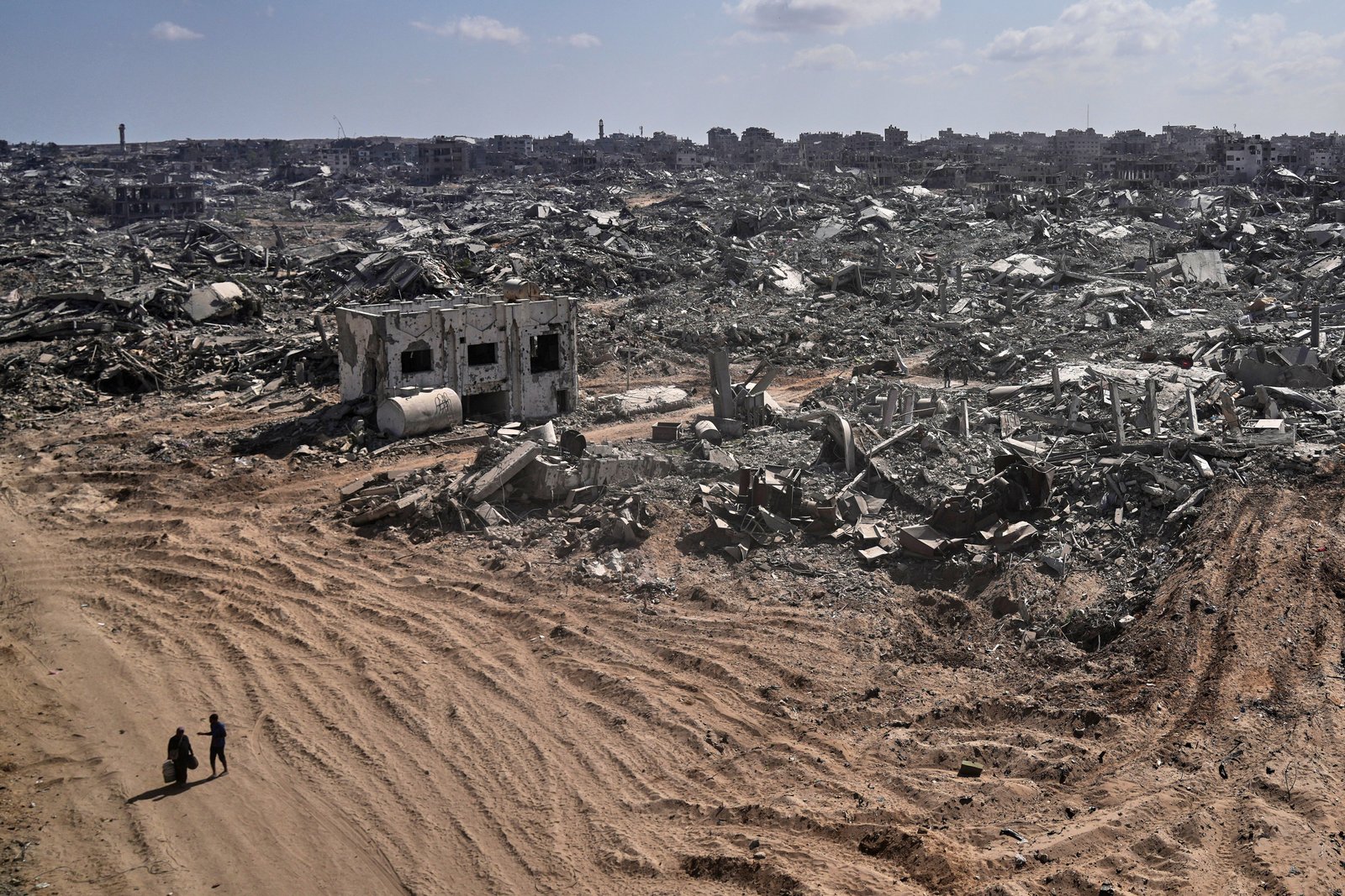 Two displaced Palestinians walk past destroyed buildings in the heavily damaged Sheikh Radwan neighborhood of Gaza City